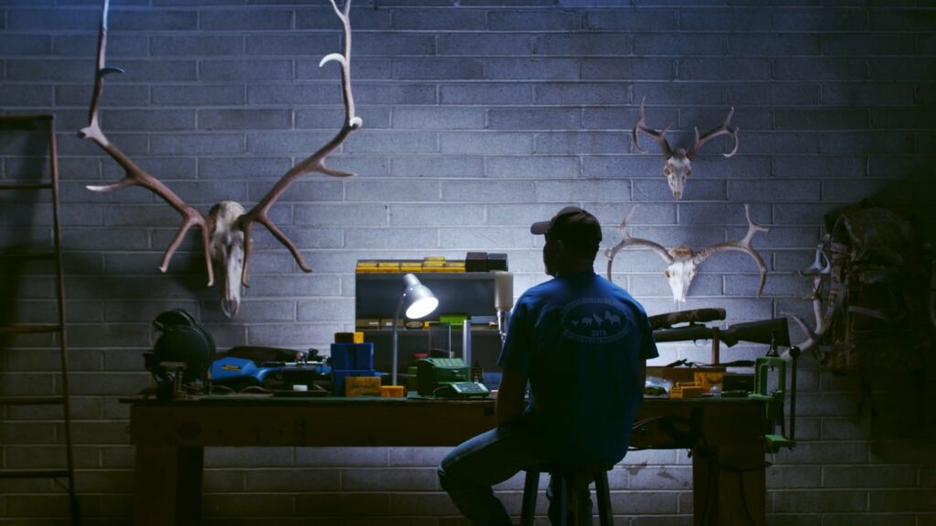 Man sitting at work bench with horned animals on the wall